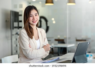 Beautiful Smiling Asian Woman Working At The Office, Looking At The Camera.