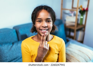 Beautiful smiling black deaf girl using sign language at home - Powered by Shutterstock