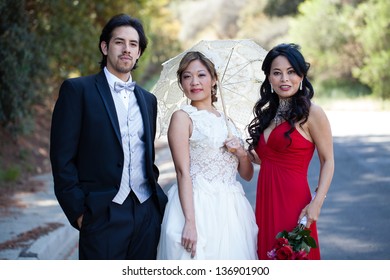 Beautiful Smiling Bride, Groom And Maid Of Honor In The Park