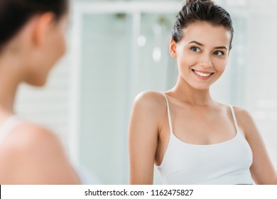 Beautiful Smiling Brunette Girl In Underwear Looking At Mirror In Bathroom  