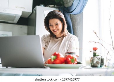 Beautiful Smiling Brunette Young Woman Plus Size Body Positive Using Laptop In Kitchen At Home