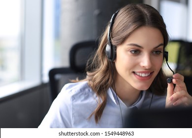 Beautiful smiling call center worker in headphones is working at modern office