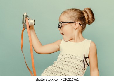 Beautiful smiling child (kid, girl) holding a instant camera - Powered by Shutterstock