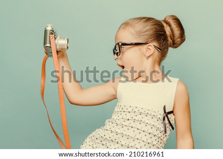 Beautiful smiling child (kid, girl) holding a instant camera