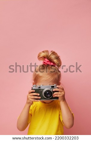 Beautiful smiling child (kid, girl) holding a instant camera. Learn photography and advertisement concept