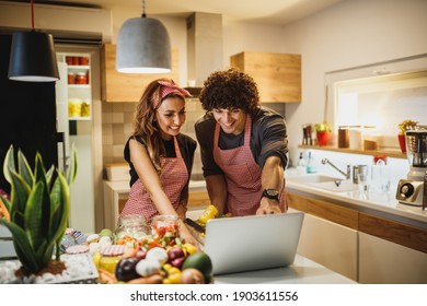 A Beautiful Smiling Couple Trying Out A New Recipe In The Kitchen Together.