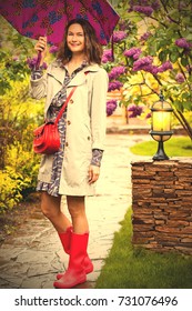 Beautiful Smiling European Woman Dressed Up In A Raincoat With An Umbrella In The Park. Style And Fashion. Instagram Image Filter Retro Style