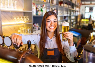 Beautiful smiling female Bartender serving a draft beer at the bar counter , shelves full of bottles with alcohol on the background - Powered by Shutterstock