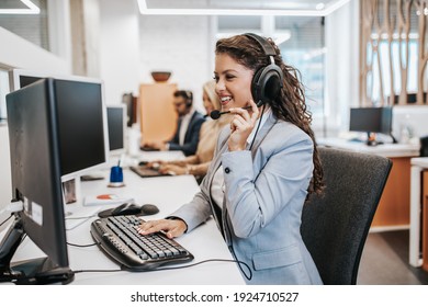 Beautiful smiling female call center worker accompanied by her team working in the office. 