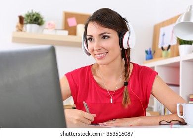 Beautiful smiling female student using online education service. Young woman looking in laptop display watching training course and listening it with headphones. Modern study technology concept - Shutterstock ID 353516087