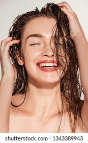 beautiful smiling girl with coral lips and wet hair posing isolated on grey
