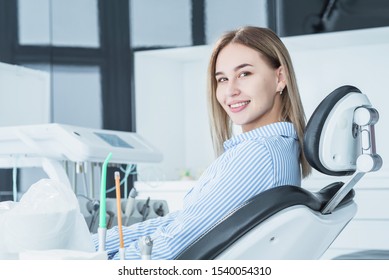 A Beautiful, Smiling Girl Examined By A Dentist, Is Sitting In A Dental Chair