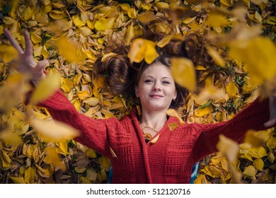 Beautiful smiling girl lying in fallen leaves in the park in autumn - Shutterstock ID 512120716