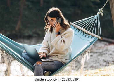 Beautiful smiling girl working with MacBook Pro in the park on a hammock