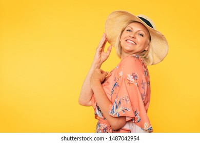 Beautiful smiling and happy cute senior woman in colorful clothes and hat is posing on yellow background. Holidays and vacation. Summer mood - Shutterstock ID 1487042954