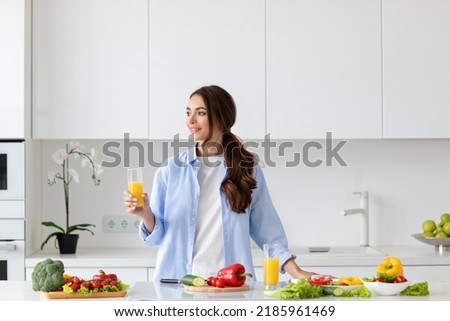 Beautiful smiling healthy woman with juice in her hands while preparing vegan food. Proper nutrition.