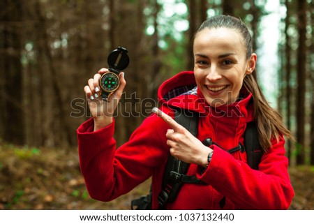Beautiful smiling hiker Woman standing outdoor in wild forest mountains and pointing on tourist compass in her hand