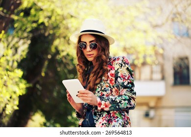 Beautiful smiling hipster woman wear vintage sunglasses, jeans shirt, white hat and jacket take a picture of herself with digital tablet. Selfie style. Toned in warm colors. Outdoors shot, lifestyle - Powered by Shutterstock