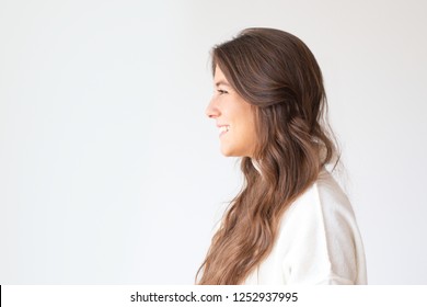 Beautiful Smiling Hispanic Girl With Long Hair, Side View. Profile Portrait Of Attractive Latin Woman Smiling And Looking Aside. Isolated On White. Beauty Concept 