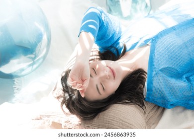 A beautiful smiling Japanese woman lying under the dazzling summer sun. Beauty images of the sea, summer tanning, ultraviolet (UV) rays. Close your eyes because of the dazzling sun. - Powered by Shutterstock