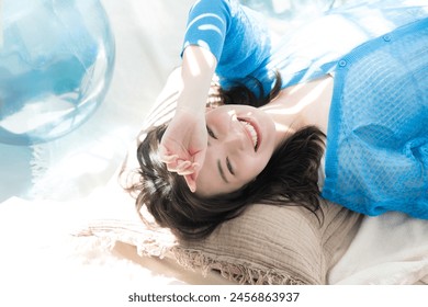 Beautiful smiling Japanese woman lying down under the dazzling summer sun. Sea, summer tanning, ultraviolet (UV) light, and other beauty images. Blinded by the dazzling sun. - Powered by Shutterstock