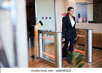 Beautiful Smiling Lady With Travel Suitcase Walking Through Automated Airport Border Gates Stock Photo