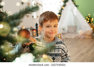 Beautiful smiling little boy standing near Christmas tree