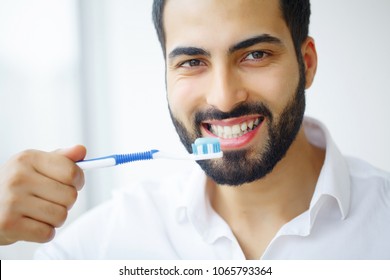 Beautiful Smiling Man Brushing Healthy White Teeth With Brush. High Resolution Image