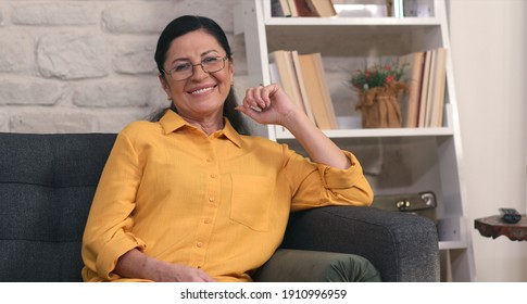 Beautiful smiling mature adult woman looking at camera. Confident happy mature old 50s retired woman posing at home. 