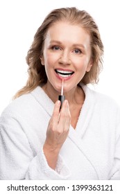 Beautiful Smiling Mature Woman Applying Lip Gloss Isolated On White 