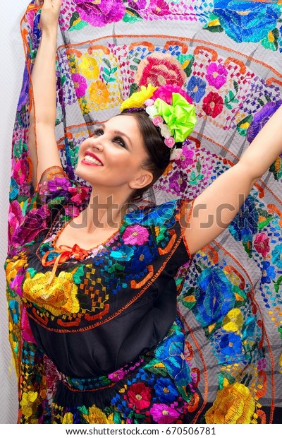 beautiful smiling\
mexican woman in traditional mexican dress hands up holding the\
skirt as a background like\
peacock