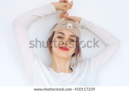 beautiful smiling model wearing a sleep mask on white