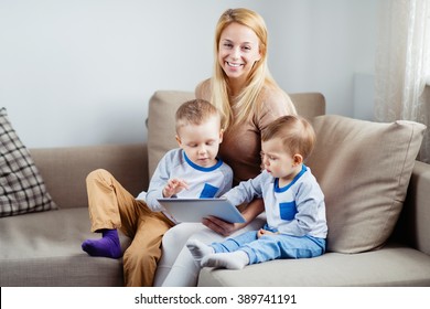 Beautiful smiling mother with her sons playing digital tablet
