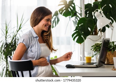 Beautiful Smiling Pregnant Woman Buying Baby Stuff Online From A Safety Of Her Home