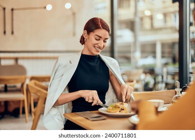 A beautiful smiling red-haired woman, eating breakfast at the restaurant. - Powered by Shutterstock