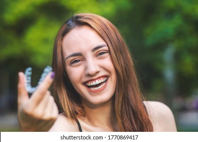 Beautiful smiling Turkish woman is holding an invisalign bracer with vibrant colors