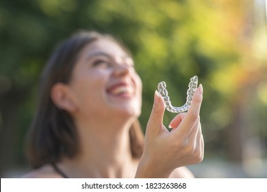 Beautiful smiling Turkish woman is holding an invisalign bracer with copy space