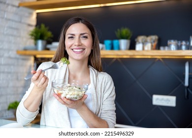 Beautiful Smiling Woman Eating Fresh Organic Vegetarian Salad In Her Kitchen,looking At Camera.