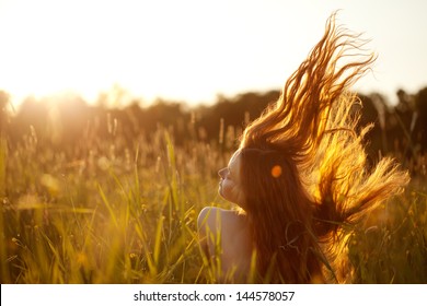 Beautiful Smiling Woman In A Field At Sunset