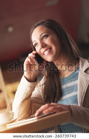 Beautiful smiling woman having a phone call and leaning on a table