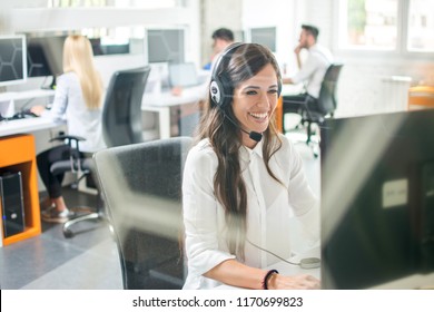 Beautiful smiling woman with headphones using computer while counseling at call center