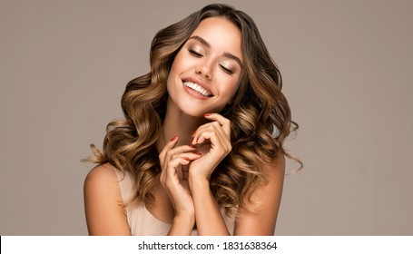 Beautiful smiling woman holding hands near face. Beauty girl  with curly hair   . Presenting your product. Expressive facial expressions . Wavy hairstyle