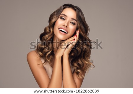 Beautiful smiling woman holding hands near face. Beauty girl  with curly hair   . Presenting your product. Expressive facial expressions
