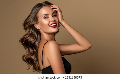 Schöne lächelnde Frau mit langwelligen Haaren.  Girl-Frisur und rote Maniküre. Schönheit, Make-up und Kosmetik.