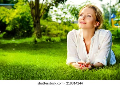 Beautiful smiling woman lying on a grass outdoor. She is absolutely happy.  - Powered by Shutterstock