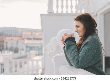 Beautiful Smiling Woman Relaxing And Drinking Coffee On The Balcony In The Morning