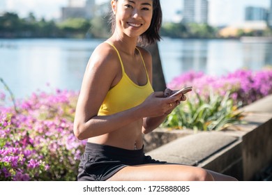 Beautiful smiling woman in sportswear holding mobile phone and looking in camera stock photo