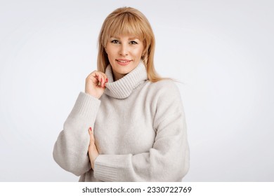 Beautiful smiling woman standing against isolated gray background. Blond haired woman wearing turtleneck sweater. Copy space.  - Shutterstock ID 2330722769
