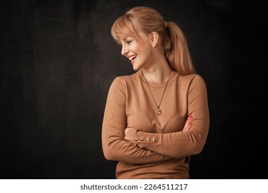 Beautiful smiling woman standing at isolated dark background. Blond haired woman wearing sweater. Copy space. Profile view. - Powered by Shutterstock