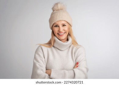 Beautiful smiling woman standing at isolated white background. Blond haired woman wearing knit heat and turtleneck sweater. Copy space.  - Powered by Shutterstock